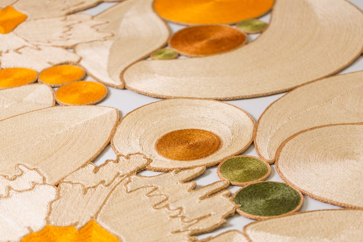 Close view of a cream sisal piece with rounded orange and olive-green forms